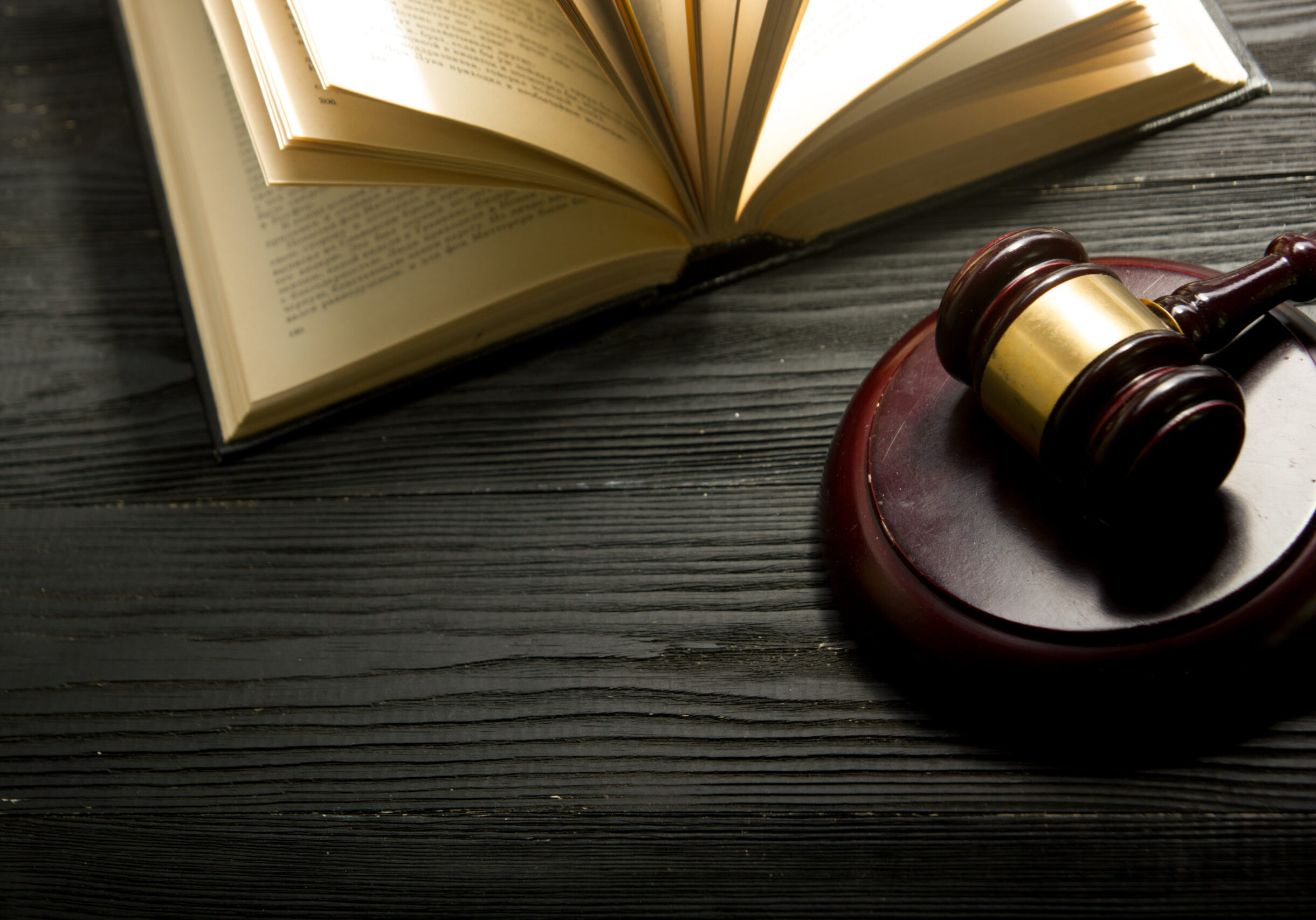 Law concept - Open law book with a wooden judges gavel on table in a courtroom or law enforcement office isolated on white background. Copy space for text