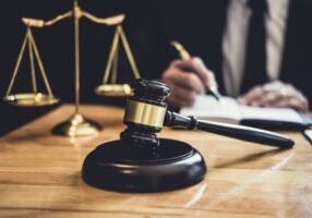 Male lawyer or judge working with contract papers, Law book and wooden gavel on table in courtroom, Justice lawyers at law firm, Law and Legal services concept.